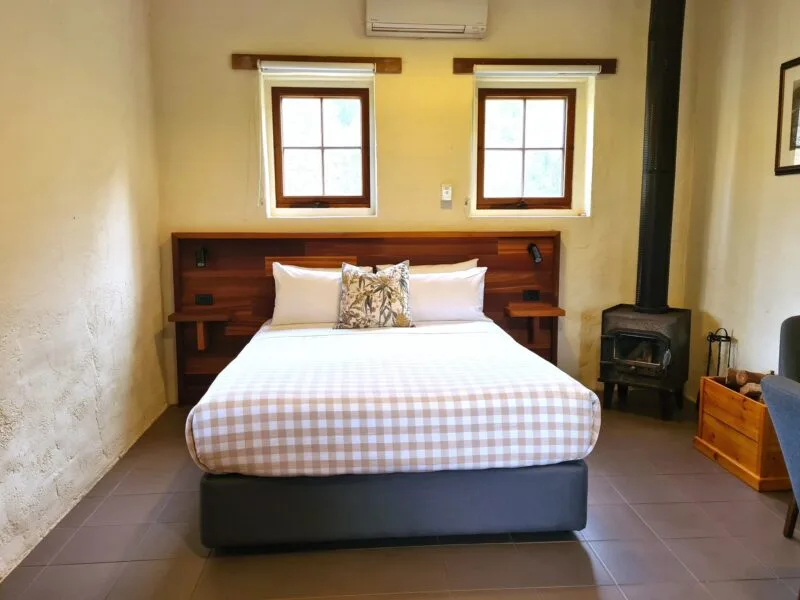 Queen size bed in Stallion Box next to a wood combustion heater